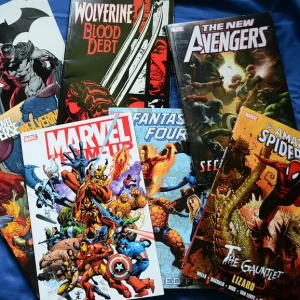 Verschiedene Marvel und DC Comics liegen auf einem blauen Hintergrund. Es ist Batman, Wolverine Blood Debt, The New Avengers, Marvel Team Up, Fantastic Four und The Amazing Spiderman zu sehen.