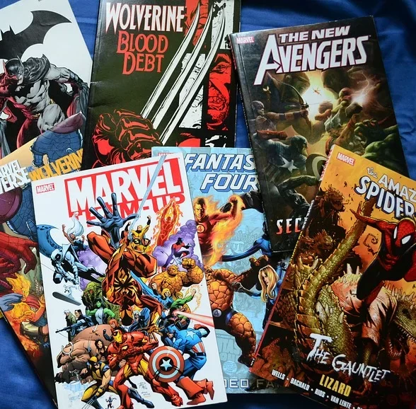 Verschiedene Marvel und DC Comics liegen auf einem blauen Hintergrund. Es ist Batman, Wolverine Blood Debt, The New Avengers, Marvel Team Up, Fantastic Four und The Amazing Spiderman zu sehen.